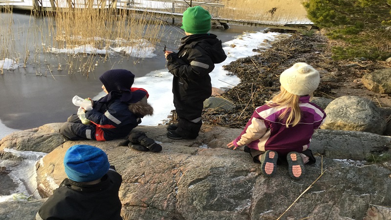 Barn leker på en klippa vid havet.