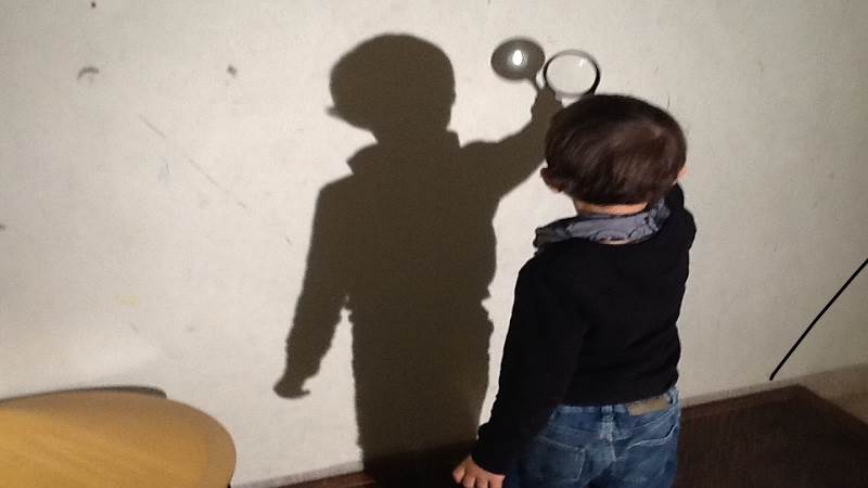 Pojke leker med skuggor. Barn med förstorningsglas.